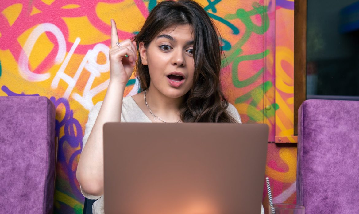 Funny young woman in front of a laptop with a surprised look.